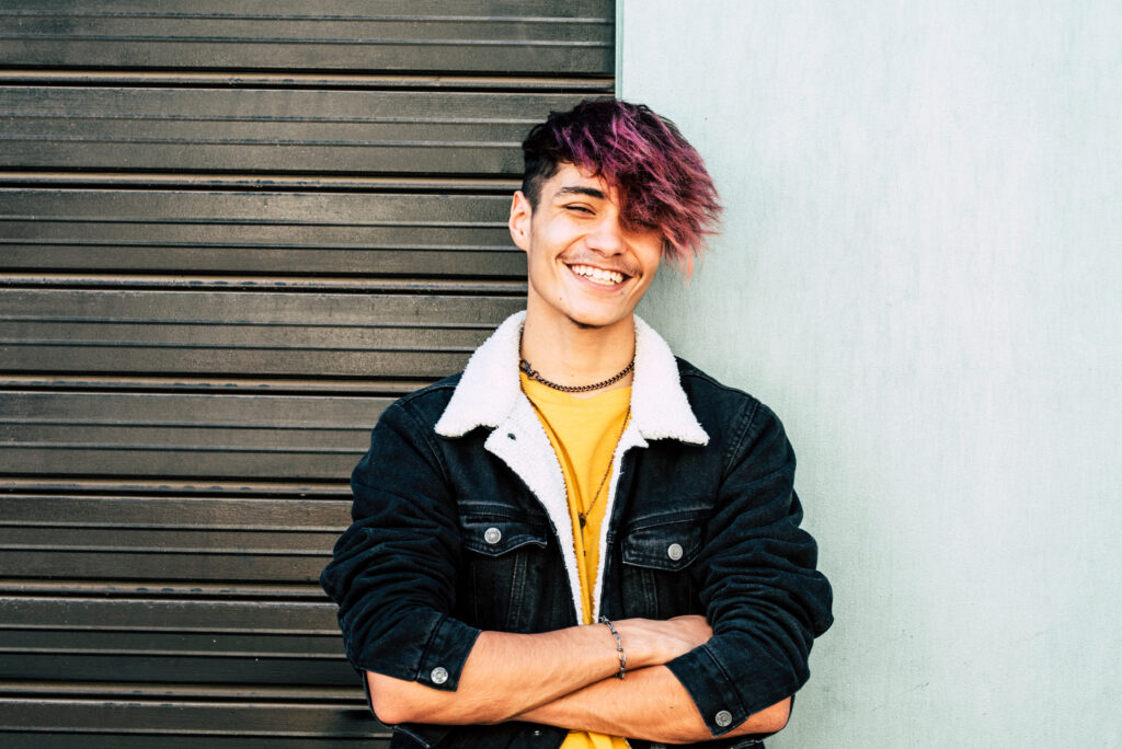 Cheerful portrait of caucasian young man teenager smiling at the camera - two colors background gray and white - urban people style having fun in outdoor
